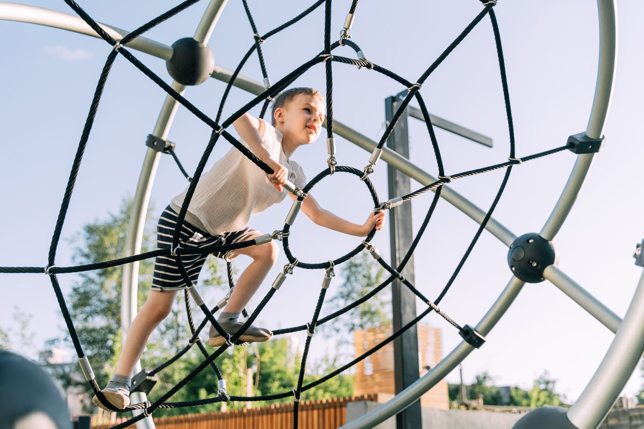 Ein junge klettert auf auf einem Spielplatz auf ein Gerüst